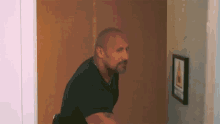a man in a black shirt is looking at a picture on a wall