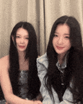 two girls with long black hair are sitting next to each other