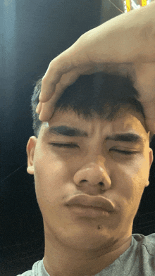 a young man holds his hand to his forehead while making a face