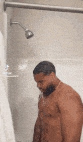 a shirtless man is taking a shower in a shower head .