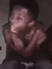 a blurry picture of a man making a funny face with his hands
