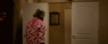 a woman in a pink shirt is standing in a room with two doors open