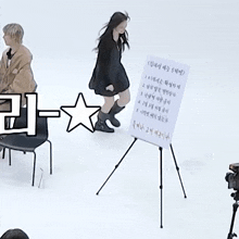 a woman in a black dress is standing in front of a white board with korean writing