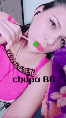 a woman in a pink top is licking a lollipop with the word chupa bb on the bottom