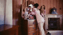 a woman in a pink dress is looking at herself in the mirror