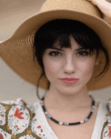 a woman wearing a straw hat and a necklace with beads