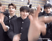 a group of young men are standing in a room with their hands in the air