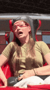 a woman wearing goggles is sitting on a roller coaster with her mouth open