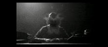 a man in a gas mask sits at a desk in a dark room