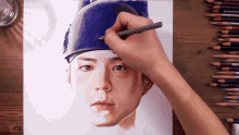 a person is drawing a portrait of a man wearing a blue hat with a pencil
