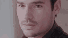 a close up of a man 's face with a beard and mustache looking at the camera .