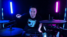 a man wearing a black shirt with a skull on it playing drums