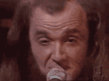 a man with long hair is singing into a microphone