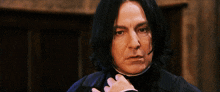 a man with long black hair has his hand on his collar