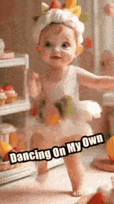 a baby girl is dancing on her own while wearing a strawberry headband .