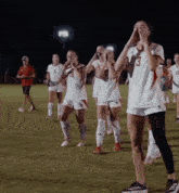 a group of female soccer players are standing on a field and one of them has the number 3 on her jersey