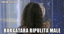 a woman with curly hair is looking out a window with the words borgatara ripulita male below her