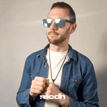 a man wearing sunglasses and a denim shirt has the word mcdh on the bottom left