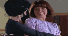 a man in a mask is holding a woman in his arms and smiling .