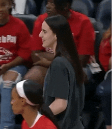 a group of people are sitting in a stadium wearing red shirts with the word time to play on them .