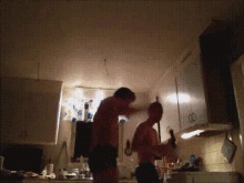 a couple of men standing in a kitchen with one holding a bottle