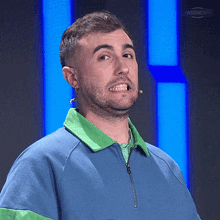 a man wearing a blue and green shirt making a face