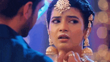a man and a woman are looking at each other and the woman is wearing a necklace and earrings .