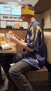a man wearing a crown eating a burger