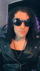 a man with curly hair wearing sunglasses and a black jacket
