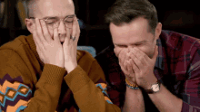 two men are laughing with their hands over their mouths