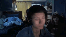 a man wearing headphones is looking at the camera in a bedroom .