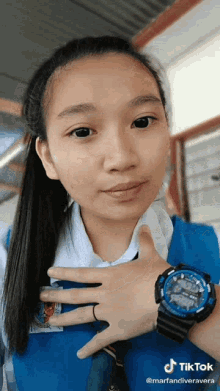 a girl wearing a blue shirt and a watch with tiktok written on the bottom right