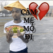 a man wearing a conical hat is holding a bowl of food with a broken heart behind him that says cam me mo di