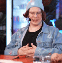 a man wearing a beanie and a denim jacket with the letter l on the back