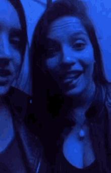 two women are posing for a picture in a dark room with blue lights