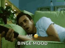 a man is laying on a couch holding a remote control with the words me binge mood above him