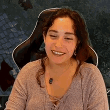 a woman is sitting in a chair and smiling while wearing headphones .