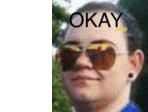 a woman wearing sunglasses is making a funny face and the word okay is on her forehead .