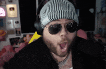 a man wearing a beanie and sunglasses makes a surprised face