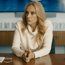 a woman sits at a table with a prime logo on the table