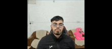 a man wearing glasses is sitting on a couch with his eyes closed
