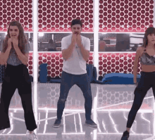 a man and two women are dancing in front of a mirror in a room .
