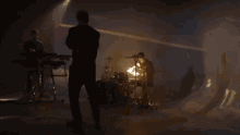 a man is playing drums in a dark room with a fire coming out of it .