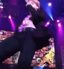 a man is dancing on stage with purple lights behind him