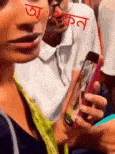 a woman is holding a cell phone with a red sticker on her face that says ' akon '