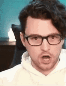 a close up of a man wearing glasses and a white hoodie .