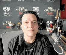 a man stands in front of a wall that says pop culture