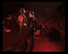 a man singing into a microphone while a woman plays a guitar