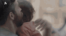 a man with a beard is hugging a woman in bed with the letter a on his head