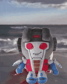 a stuffed toy of a robot with red eyes and blue arms